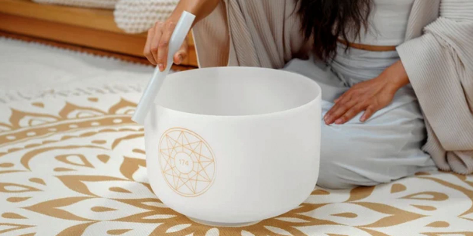 Woman playing a crystal singing bowl on a Meinl Sonic Energy mat during meditation and frequency practice