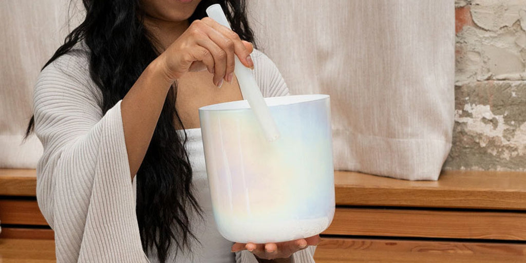 Close-up of a crystal singing bowl being played during a sound healing meditation session with quartz frequency instruments