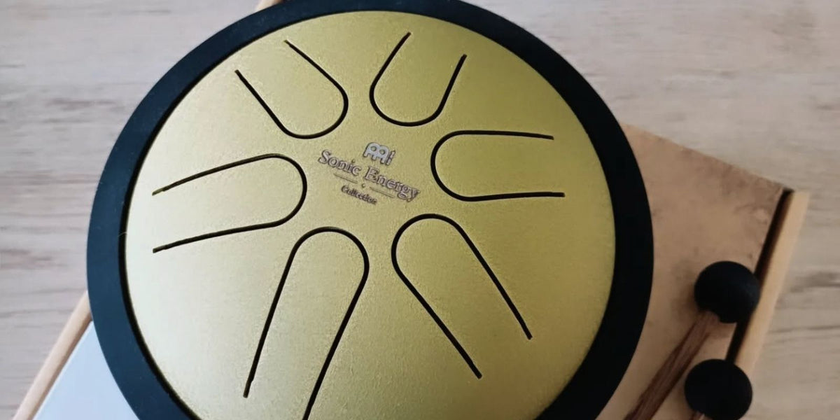 Overhead view of a Meinl Sonic Energy steel tongue drum with gold playing surface, tuned metal tongues and mallets.