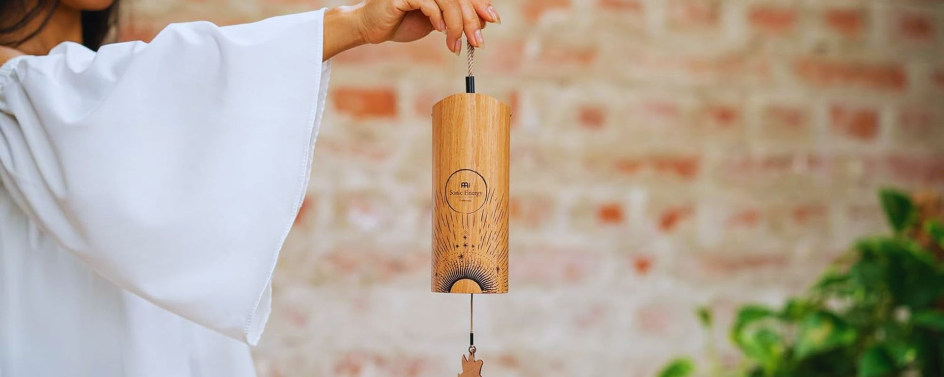 Woman holding a bamboo cosmic chime, koshi-style, during a peaceful sound healing meditation session.