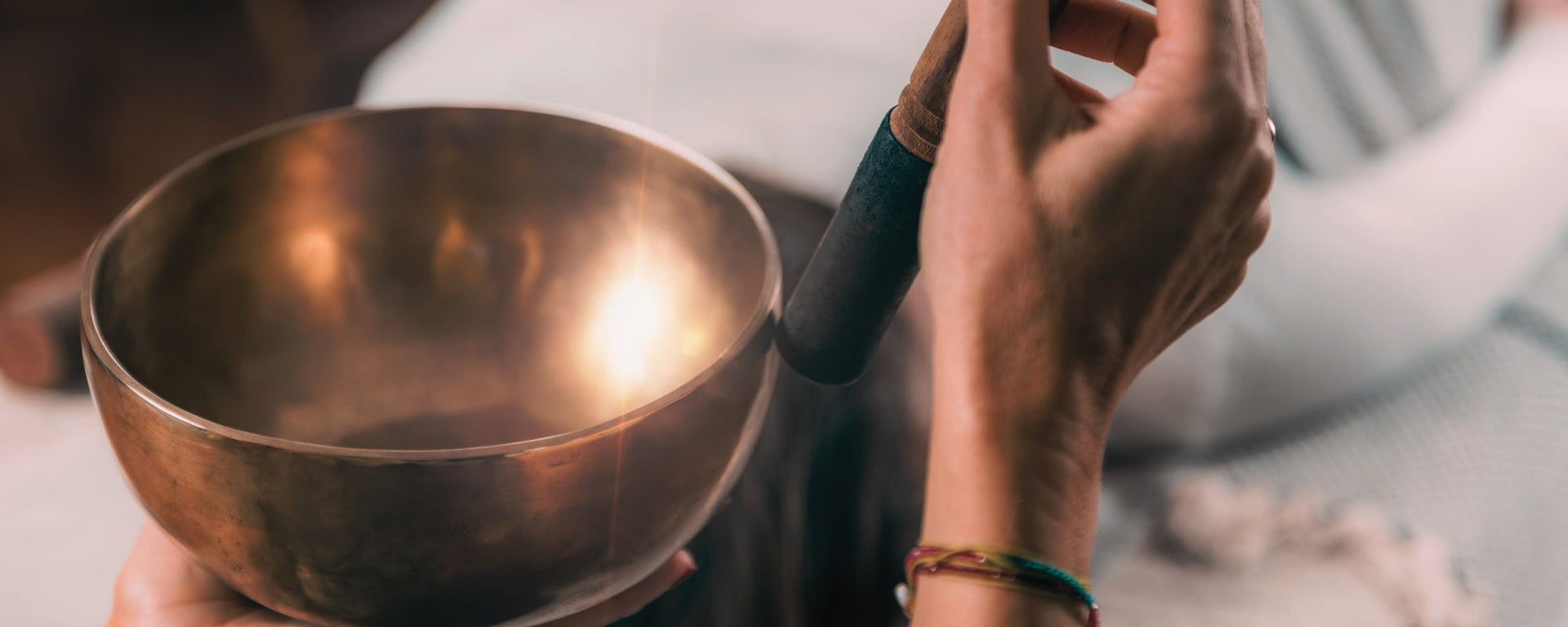 Close-up of a metal singing bowl being played during a sound therapy session, creating calming vibrations for meditation and relaxation.