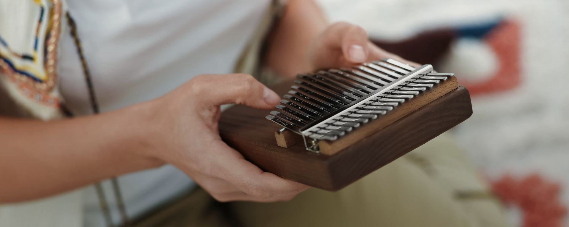 close up of woman playing a kalimba with both hands, creating gentle melodic tones for meditation, mindfulness, relaxation, and immersive sound exploration within the Sound Healing Kalimbas collection