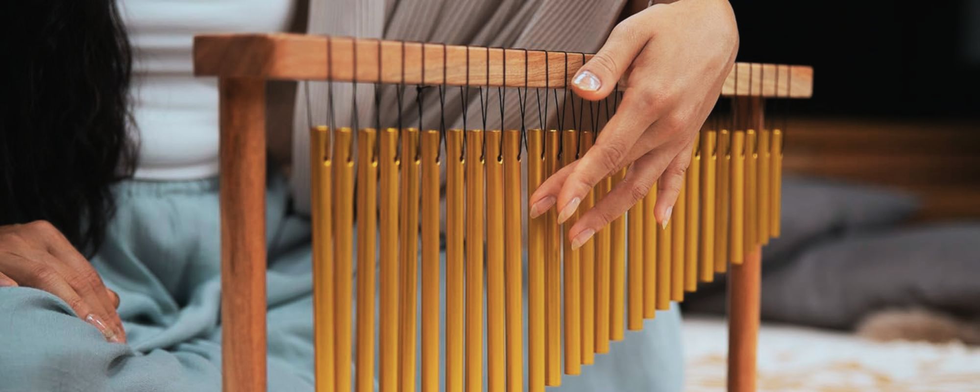 Woman playing table chimes during a relaxing sound therapy session.