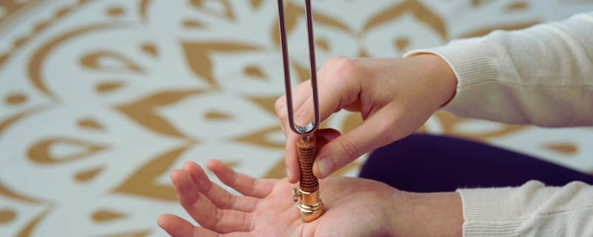 Close-up of a tuning fork held in a person’s hand during a calming sound therapy session, used for meditation, relaxation, and energy balancing.