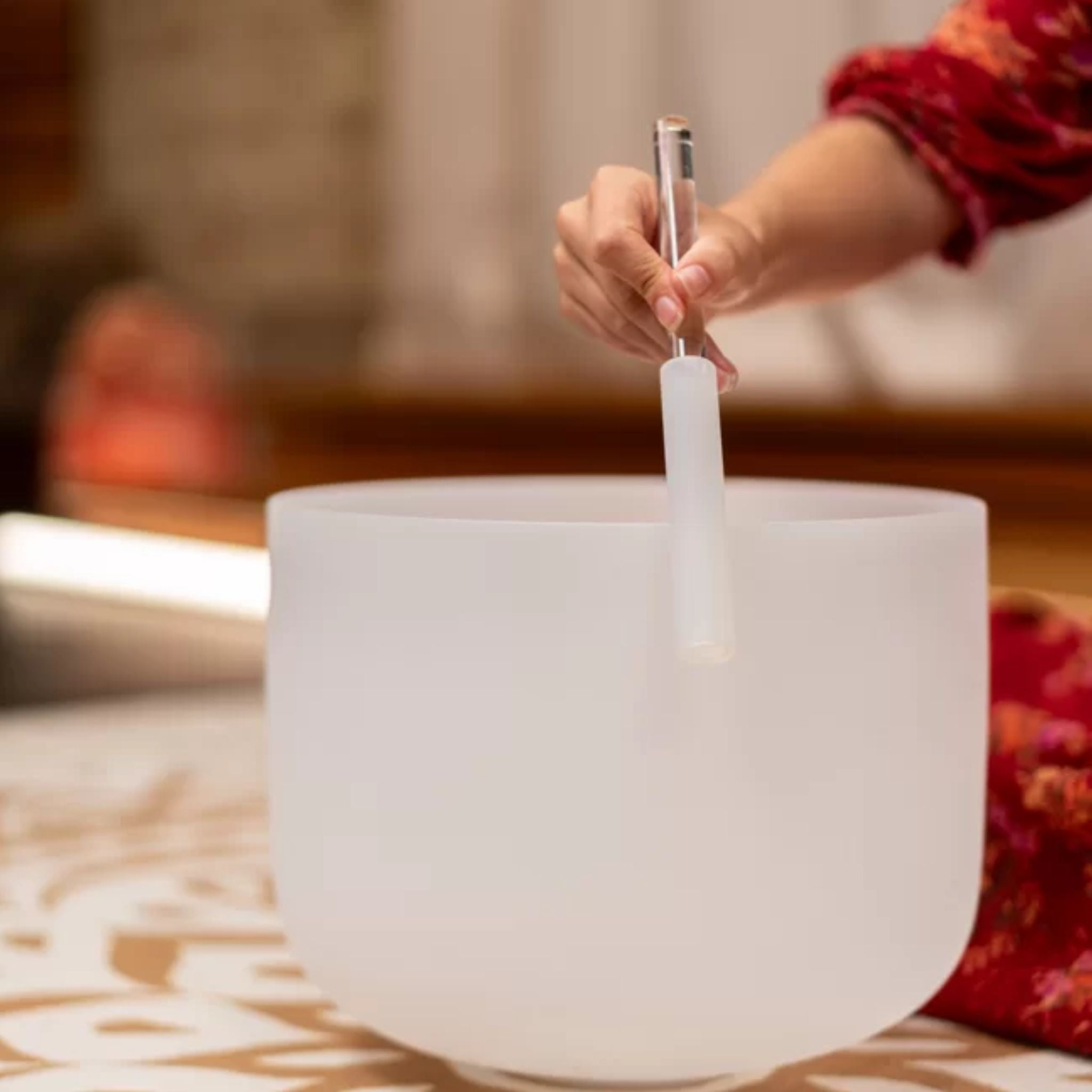 Woman playing a Meinl Sonic Energy crystal singing bowl with a mallet during a sound healing session for meditation and frequency practice