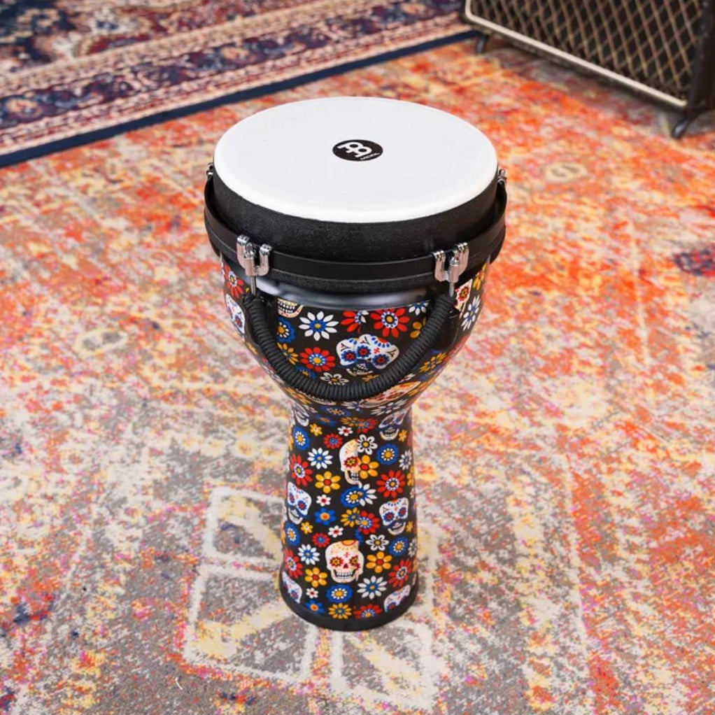 Meinl Jumbo Series Djembe Drum 10" Day of the Dead JD10DA displayed on a patterned rug in a music studio setting.