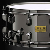 Close-up of the Tama S.L.P. Black Brass Snare Drum 14" x 6.5" LBR1465 showing the brass shell, Black Nickel hardware, lugs, and Steel Mighty Hoop.