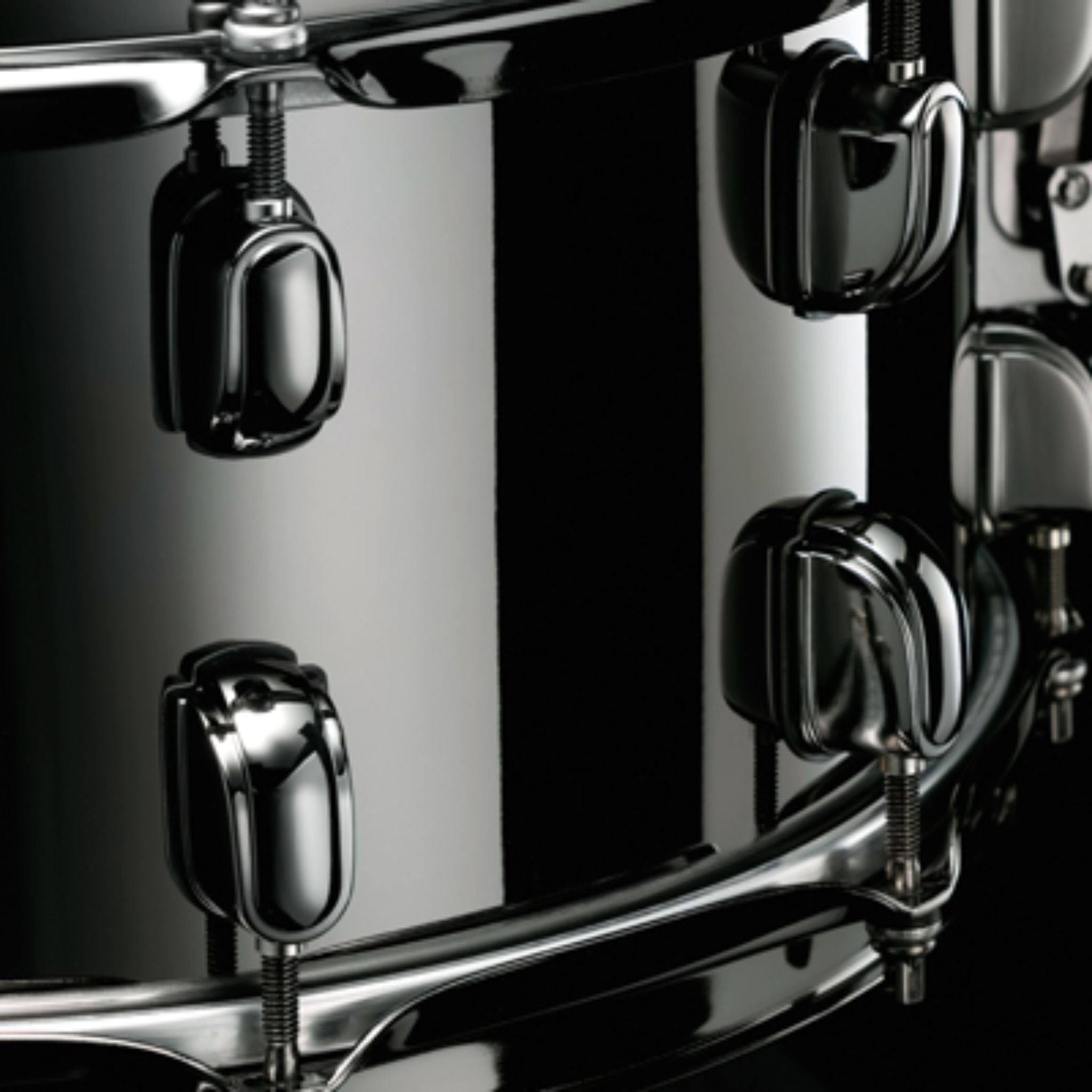 Close-up side view of the Tama S.L.P. Black Brass Snare Drum LBR1465 showing the 1.5mm brass shell, Black Nickel Starclassic lugs, and strainer hardware.