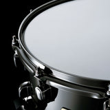 Close-up of the Tama S.L.P. Black Brass Snare Drum LBR1465 showing the snare head, 2.3mm triple-flanged Steel Mighty Hoop, and Black Nickel hardware.