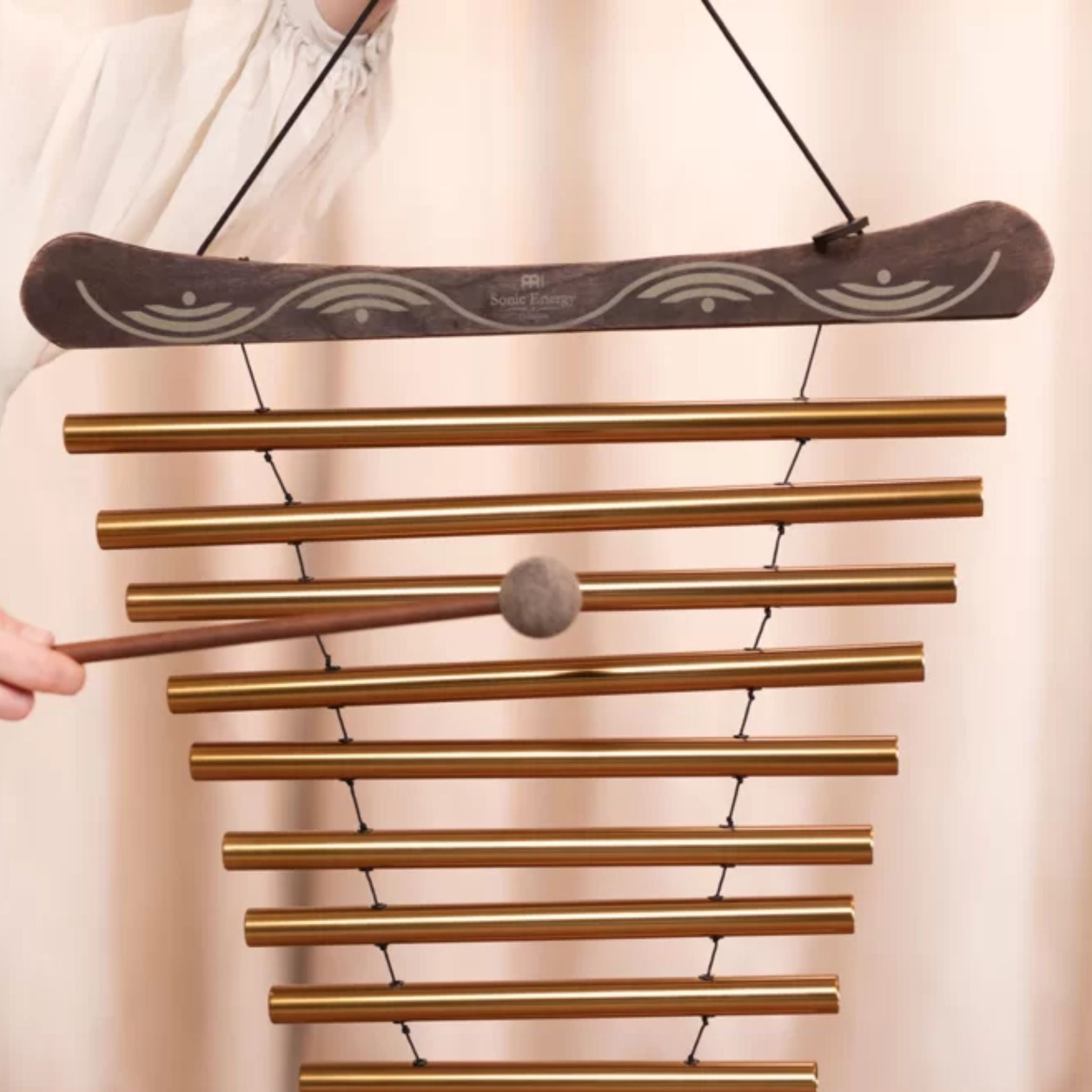 Close-up of the Meinl Sonic Energy Meditation Flow Chime 88cm 440Hz D Major Bronze MFC10DMAB being played by hand with the included mallet.