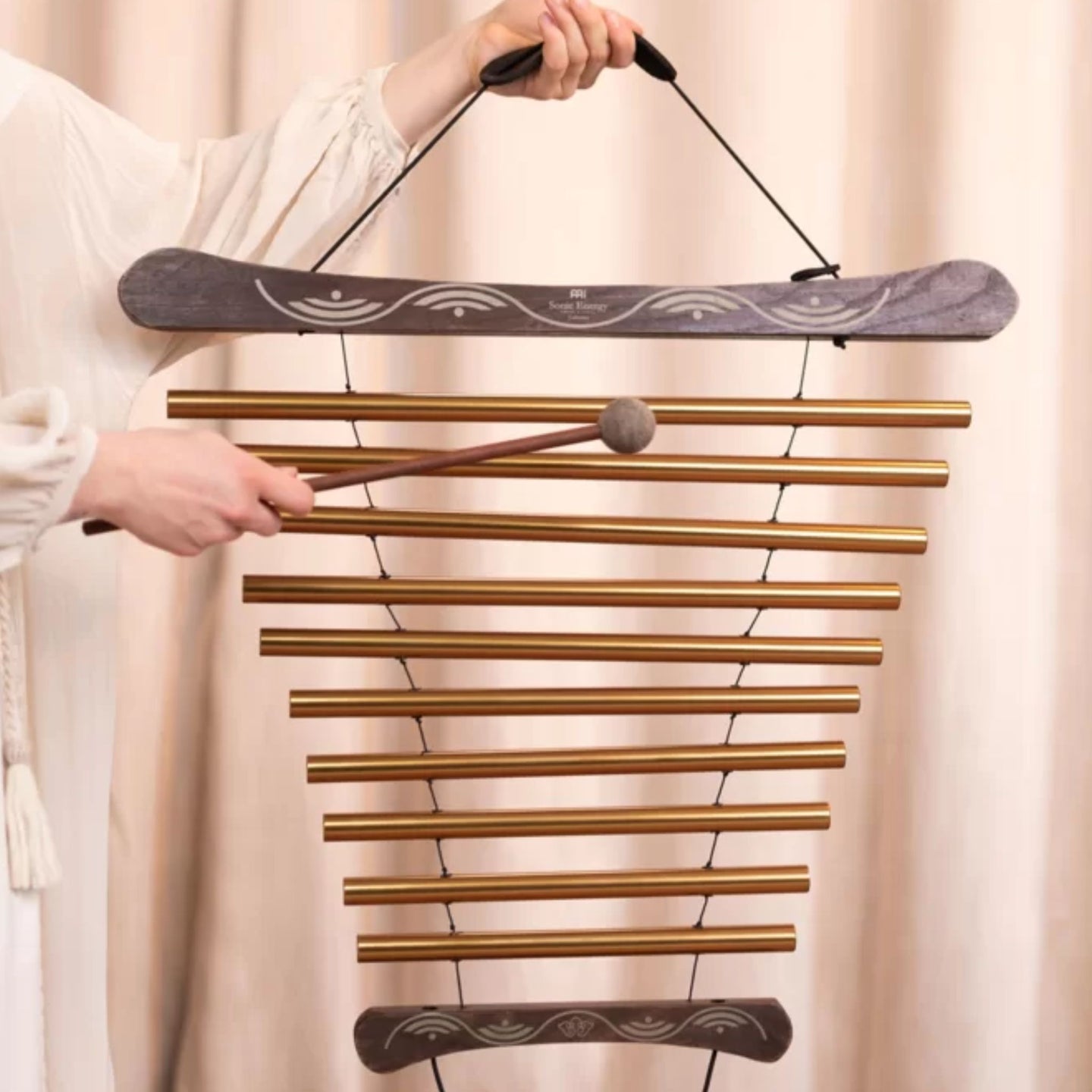 Woman playing a Meinl Sonic Energy meditation flow chime during a sound healing session to create gentle resonant tones for meditation and relaxation