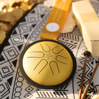 Meinl Sonic Energy 6-inch Tongue Drum Gold MSTD3G with mallet and display box on a rug for meditation and tonal exploration