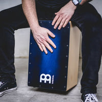 Musician playing the Meinl Snarecraft Cajon SC100BLB Blue Burst finish during an acoustic session.