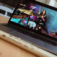 Meinl Kriss Rybalchenko Signature Drumsticks SB603 placed in front of a laptop displaying Kriss Rybalchenko performing on the drums.