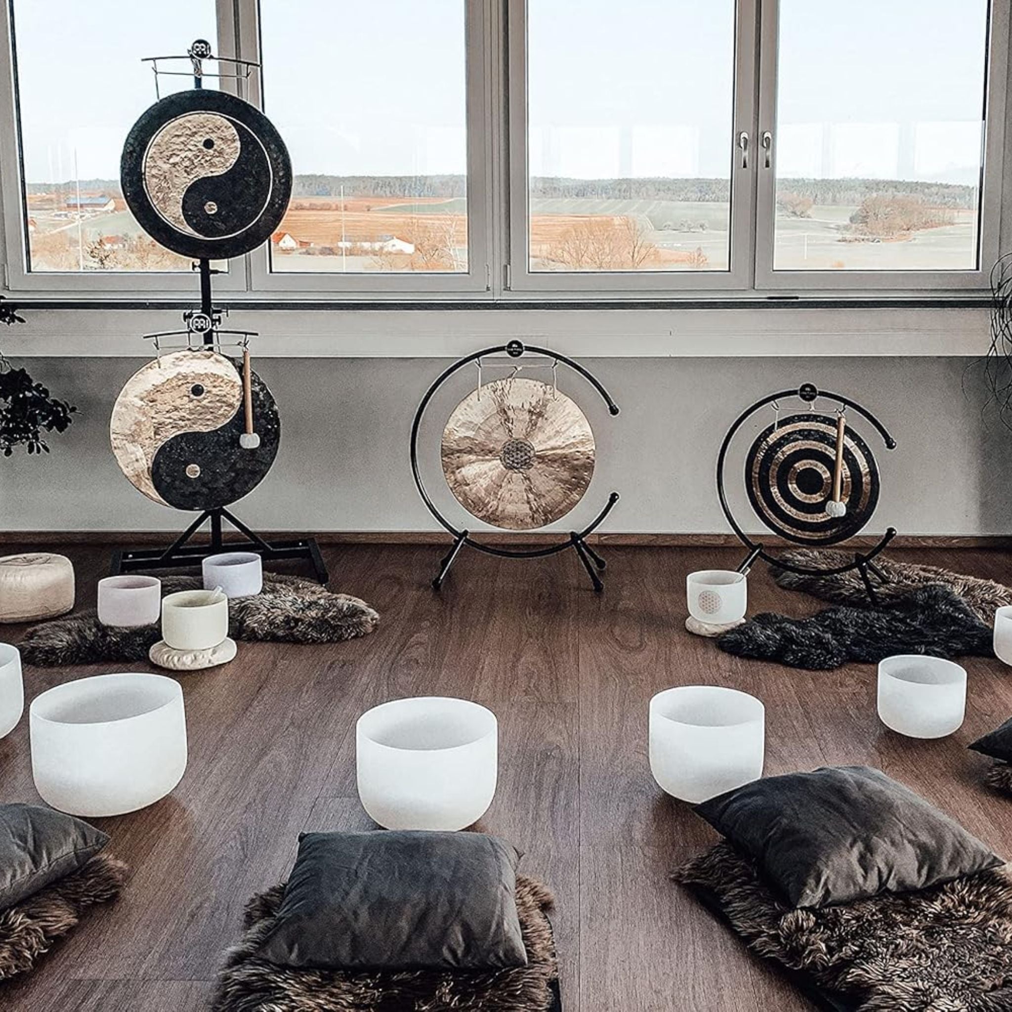 Meinl Sonic Energy Flower of Life Wind Gong on gong stand in meditation space surrounded by singing bowls, cushions, and additional gongs