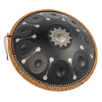 Angled view of the Mano Percussion ManoPan MPC70MBK D Kurd handpan showing the black top, silver mandala artwork and side profile.