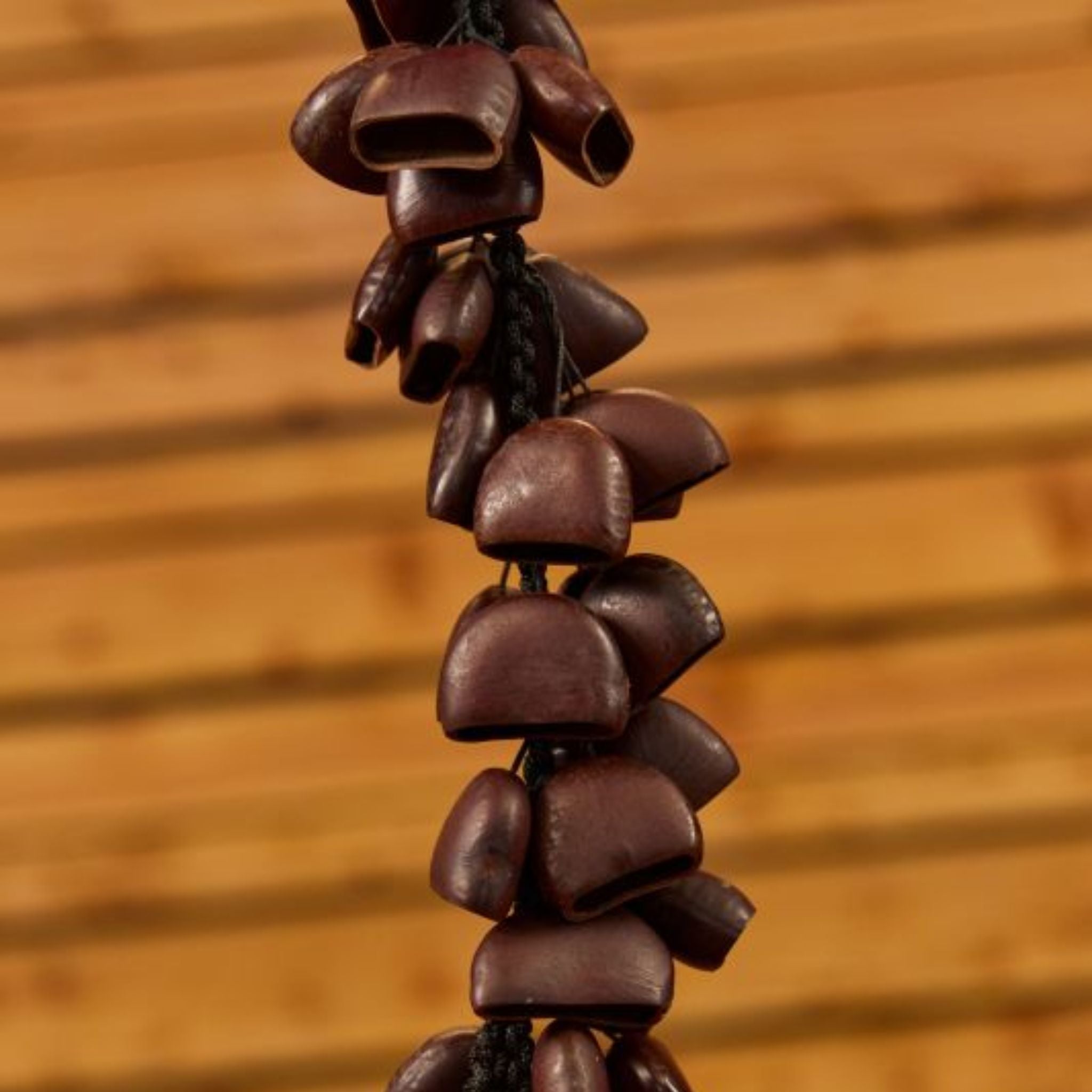 close up of middle section of Meinl Bendo Bird Shaker 40 Seeds BI5 showing natural Bendo seed nutshells and durable cord construction against wooden background