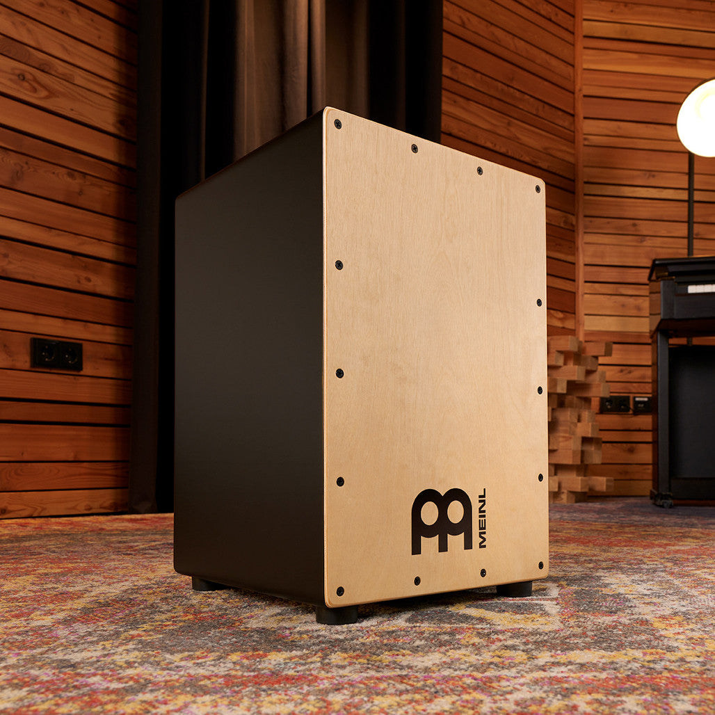 Meinl Headliner Series Snare Cajon MCAJ100BK-MA with natural maple frontplate displayed in a studio setting.