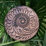 10 inch rain disk resting outdoors on palm tree branch showing Fibonacci-inspired carved surface in natural environment