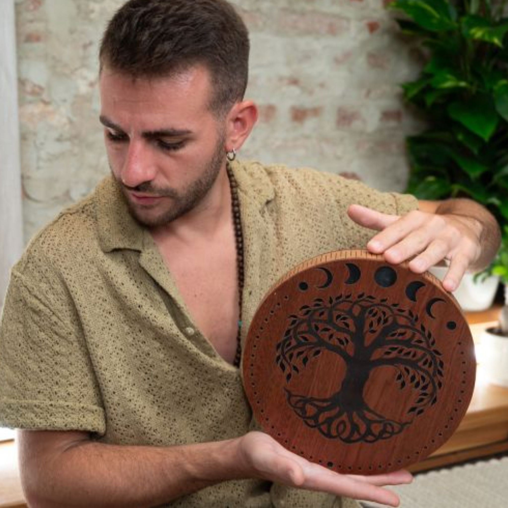 close up of man playing 10 inch rain disk during sound therapy session showing rotational hand movement and carved surface detail