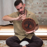 man playing 10 inch rain disk while seated cross legged during sound therapy session creating calming water-like resonance