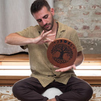 man playing 10 inch rain disk while seated cross legged during sound therapy session creating calming water-like resonance
