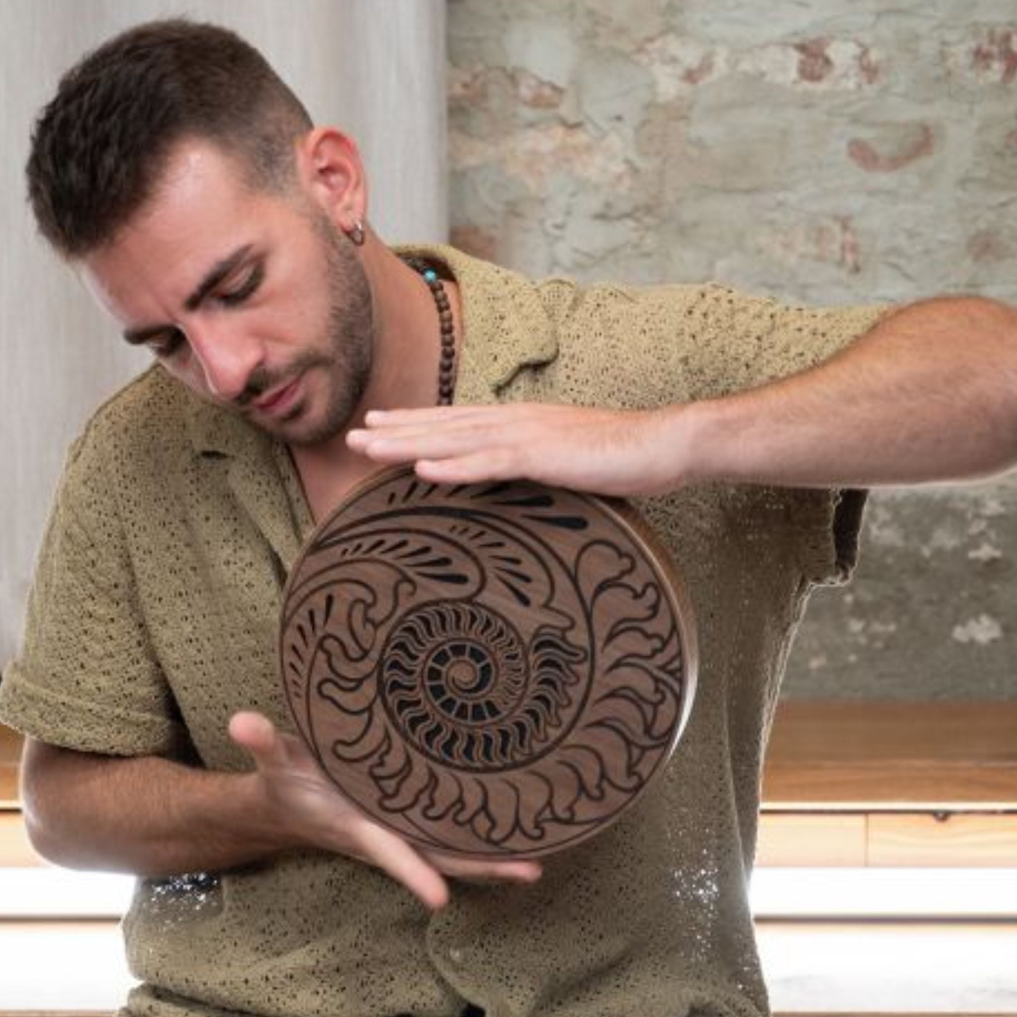 man playing 10 inch rain disk while seated cross legged during sound therapy session creating calming ocean-like resonance