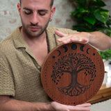 close up of man playing 12 inch rain disk during sound therapy session showing rotational hand movement and carved surface detail