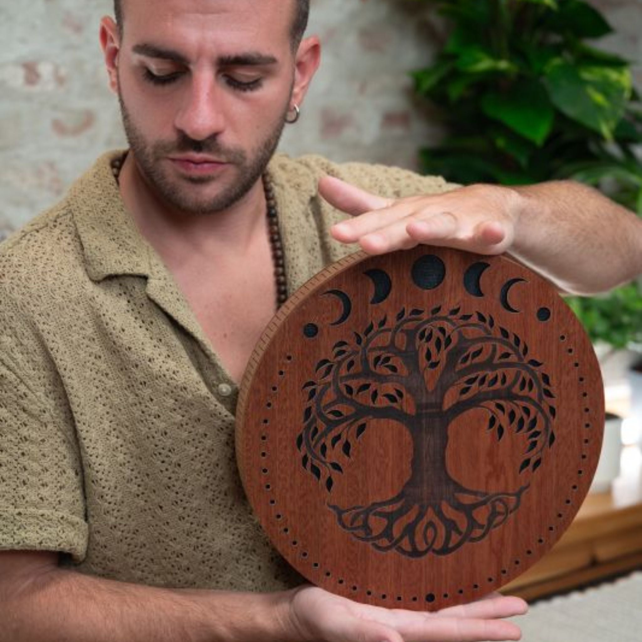 close up of man playing 12 inch rain disk during sound therapy session showing rotational hand movement and carved surface detail