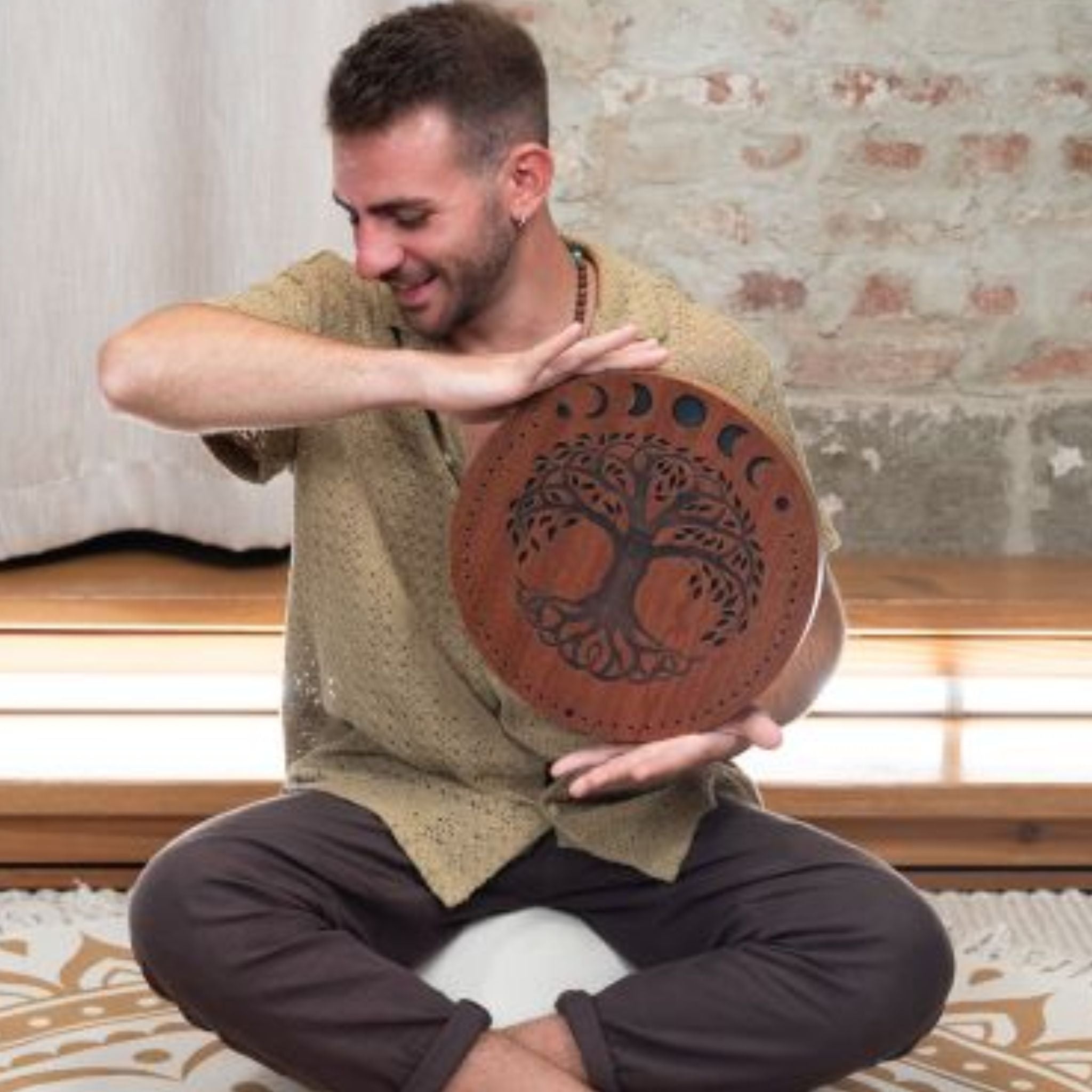 man playing 12 inch rain disk while seated cross legged during sound therapy session creating calming water-like resonance