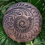15 inch rain disk resting outdoors on palm tree branch showing Fibonacci-inspired carved surface in natural environment