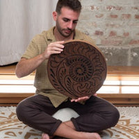 man playing 15 inch rain disk while seated cross legged during sound therapy session creating calming ocean-like resonance