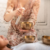 Therapist with singing a bowl set in a sound healing seeion with another a patient in complete relaxation.