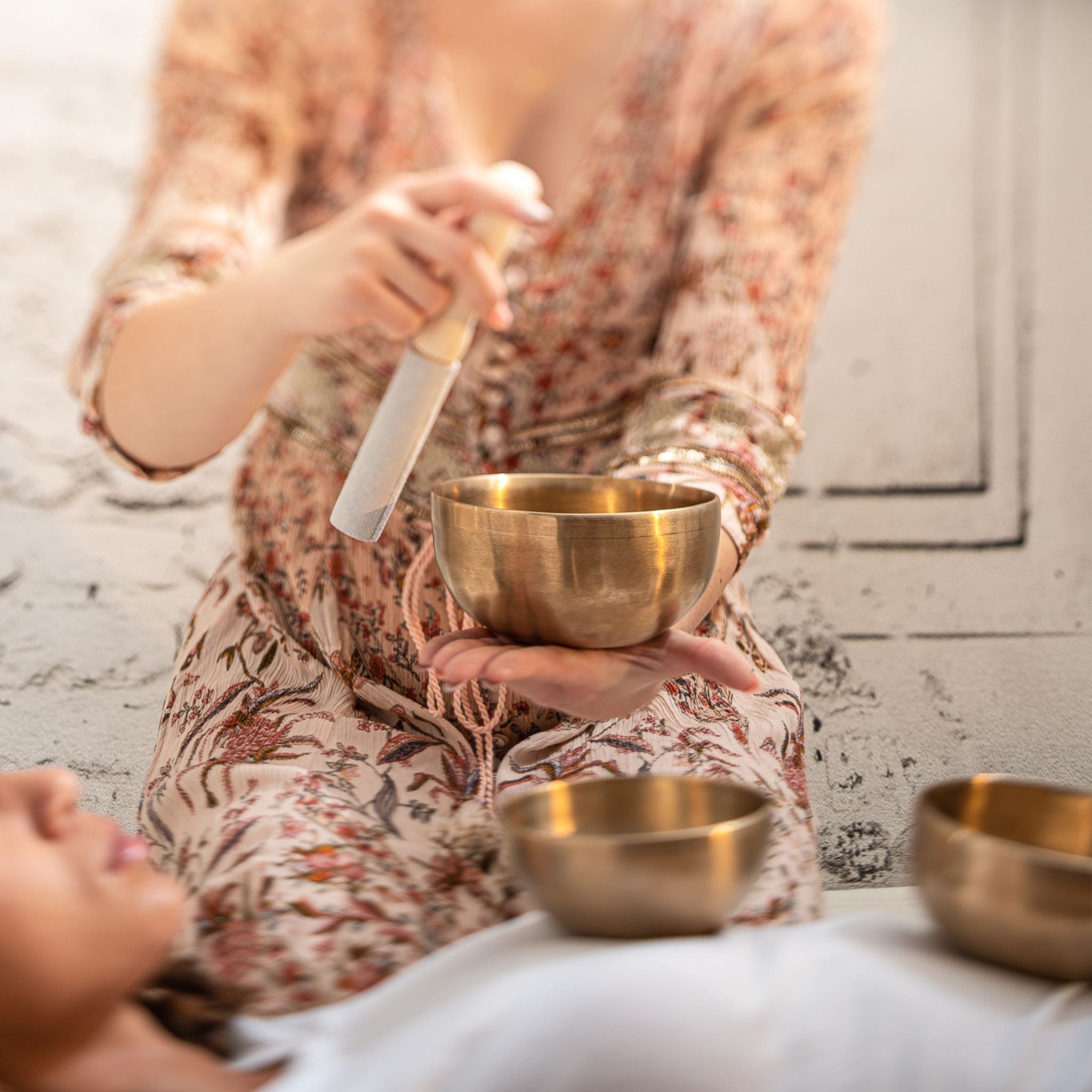 Therapist with singing a bowl set in a sound healing seeion with another a patient in complete relaxation.