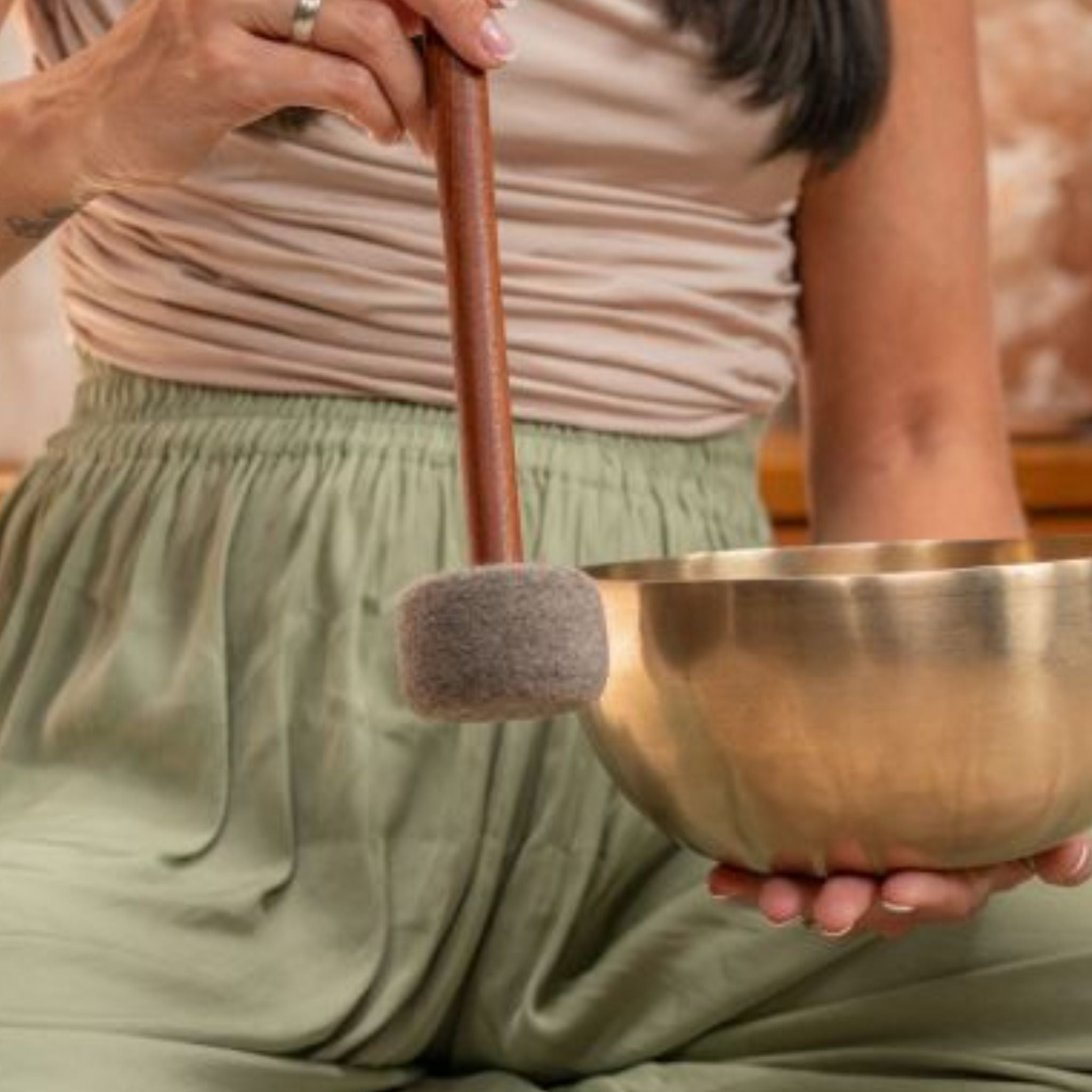 Close-up of a woman using the Meinl Sonic Energy Medium Felt Tip Mallet – Singing Bowl SB-PM-MF-M to play a metal singing bowl during meditation.