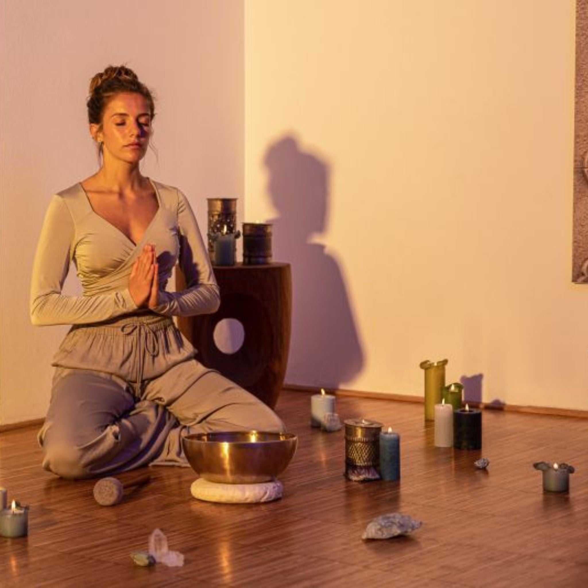 Woman meditating with metal singing bowls, candles, and the Meinl Sonic Energy Medium Felt Tip Mallet – Singing Bowl SB-PM-MF-M placed in front of her.