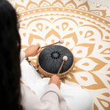 Over-the-shoulder view of a woman playing the Meinl Sonic Energy Medium Octave Steel Tongue Drum 10" B Minor 432 Hz MOSTD1BK with the included soft mallets.