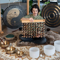 Sound practitioner seated on the floor holding Meinl Sonic Energy mixed seed chimes during a sound bath session