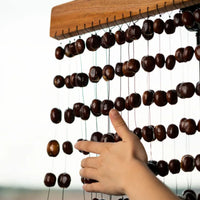 Close-up of the Meinl Sonic Energy Pala Chimes SPCH with a hand striking the natural Pala seed nutshell chimes.