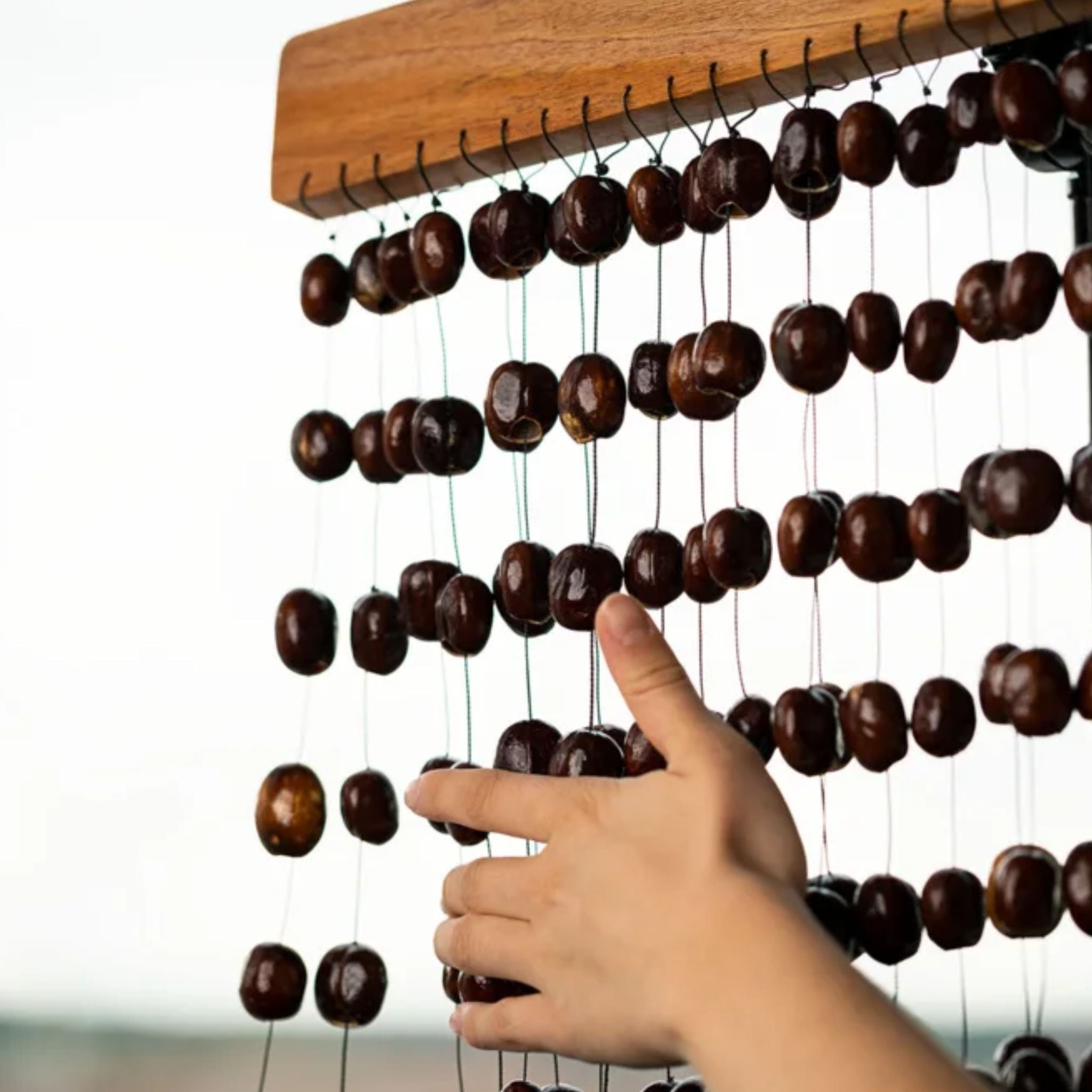 Close-up of the Meinl Sonic Energy Pala Chimes SPCH with a hand striking the natural Pala seed nutshell chimes.