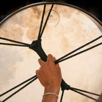 woman holding Meinl Sonic Energy Ritual Frame Drum 18 inch Goat Skin RD18WB showing rear cord cross grip and comfortable hand positioning for playing and control