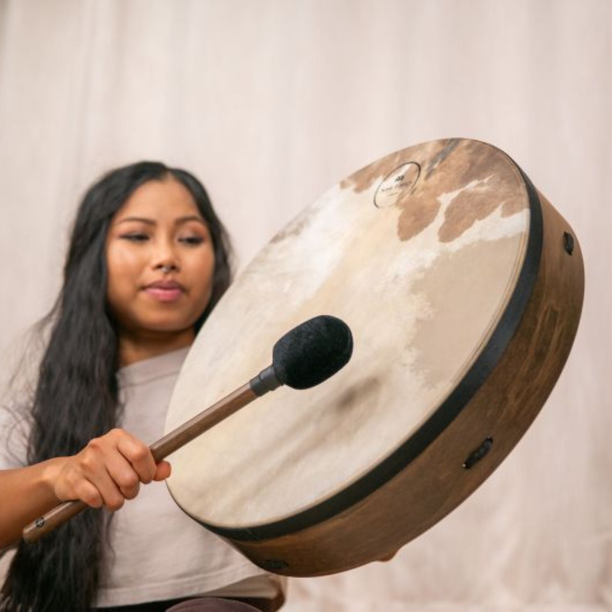 woman playing Meinl Sonic Energy Ritual Frame Drum 18 inch Goat Skin RD18WB with included mallet to create deep warm tones for meditation, sound baths, and rhythmic exploration
