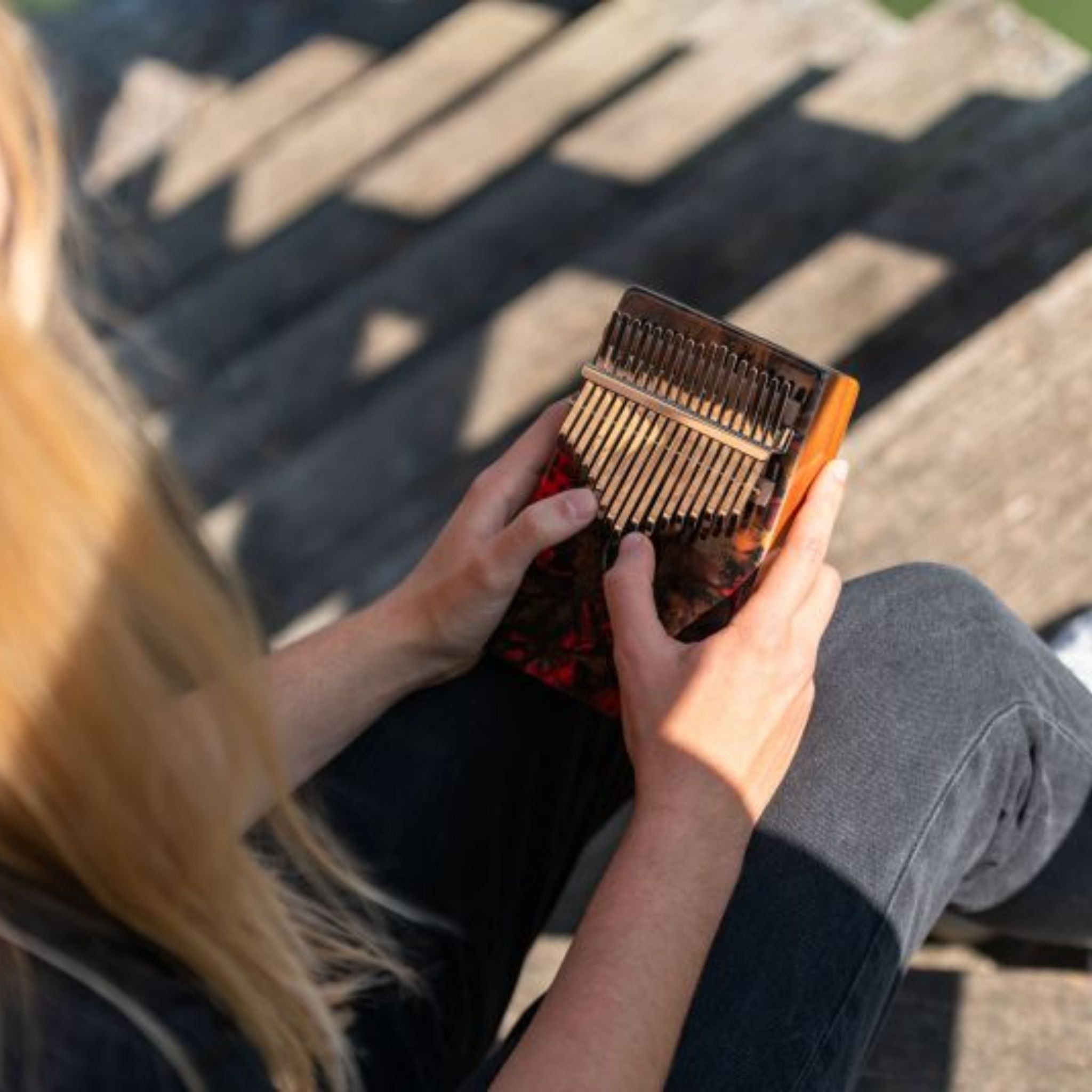 woman playing Meinl Sound Hole Designer Kalimba Lava KA17LV demonstrating melodic tones, intuitive thumb piano playing, and resonant acacia wood sound for relaxation, creativity, and sound exploration.