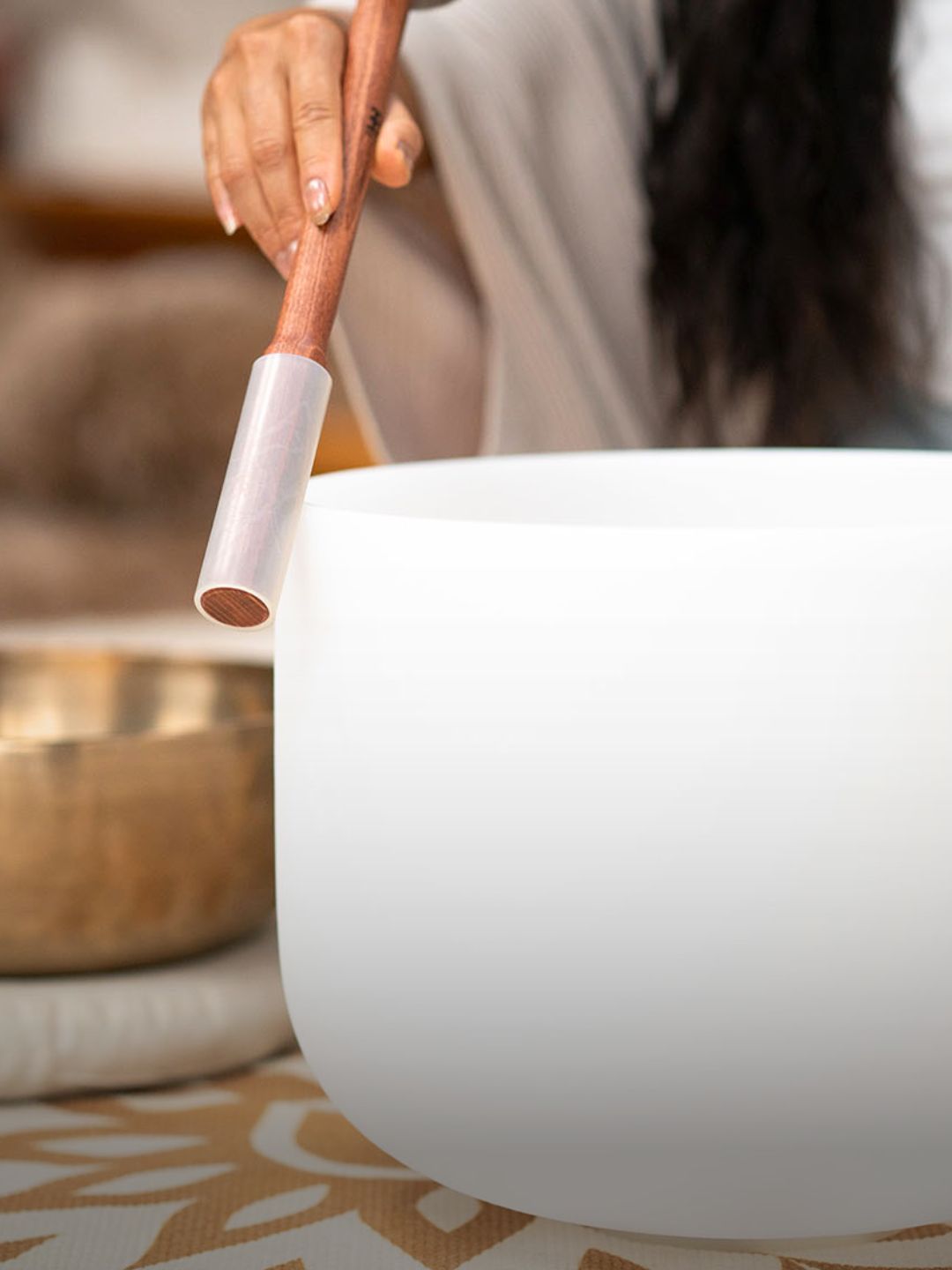Sound healing session featuring a crystal singing bowl played with a mallet, representing frequency-based instruments for meditation and therapeutic use.