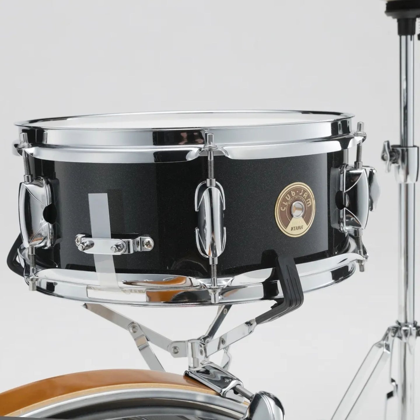 Close-up of the Tama Club-JAM Mini 12" x 5" snare drum in Charcoal Mist with part of the bass drum and hi-hat stand visible.